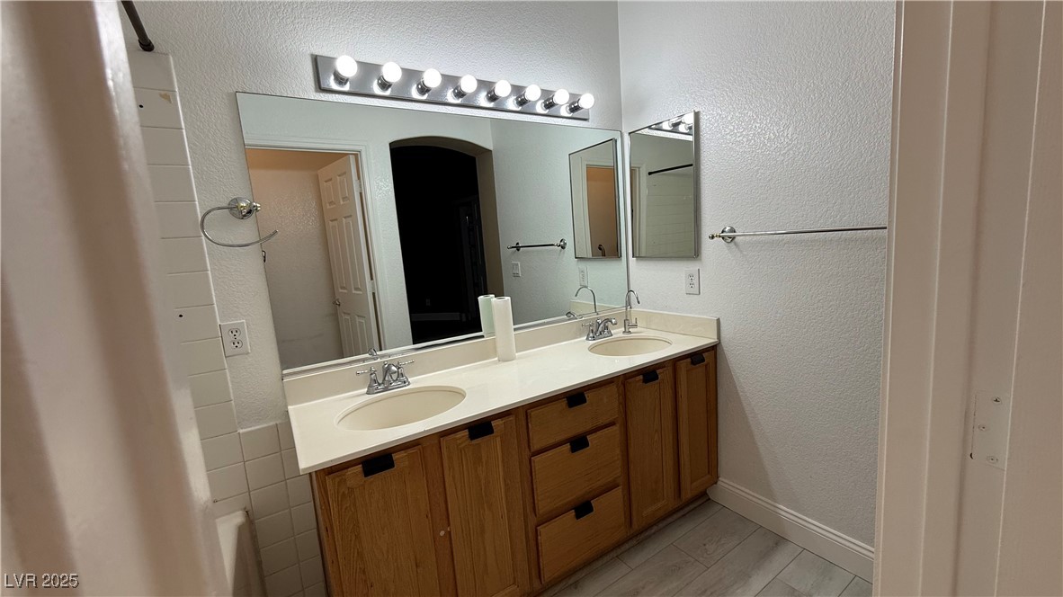 7062 Russell Ranch Avenue Las Vegas, NV 89113 - Photo 28 of 32 Bathroom featuring double vanity, baseboards, and a sink