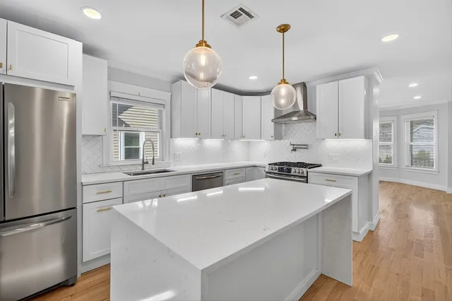 a kitchen with stainless steel appliances granite countertop a sink a stove and a refrigerator