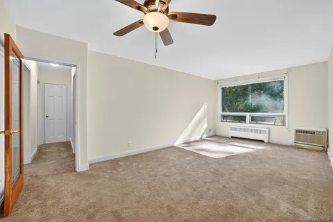 an empty room with windows and fan