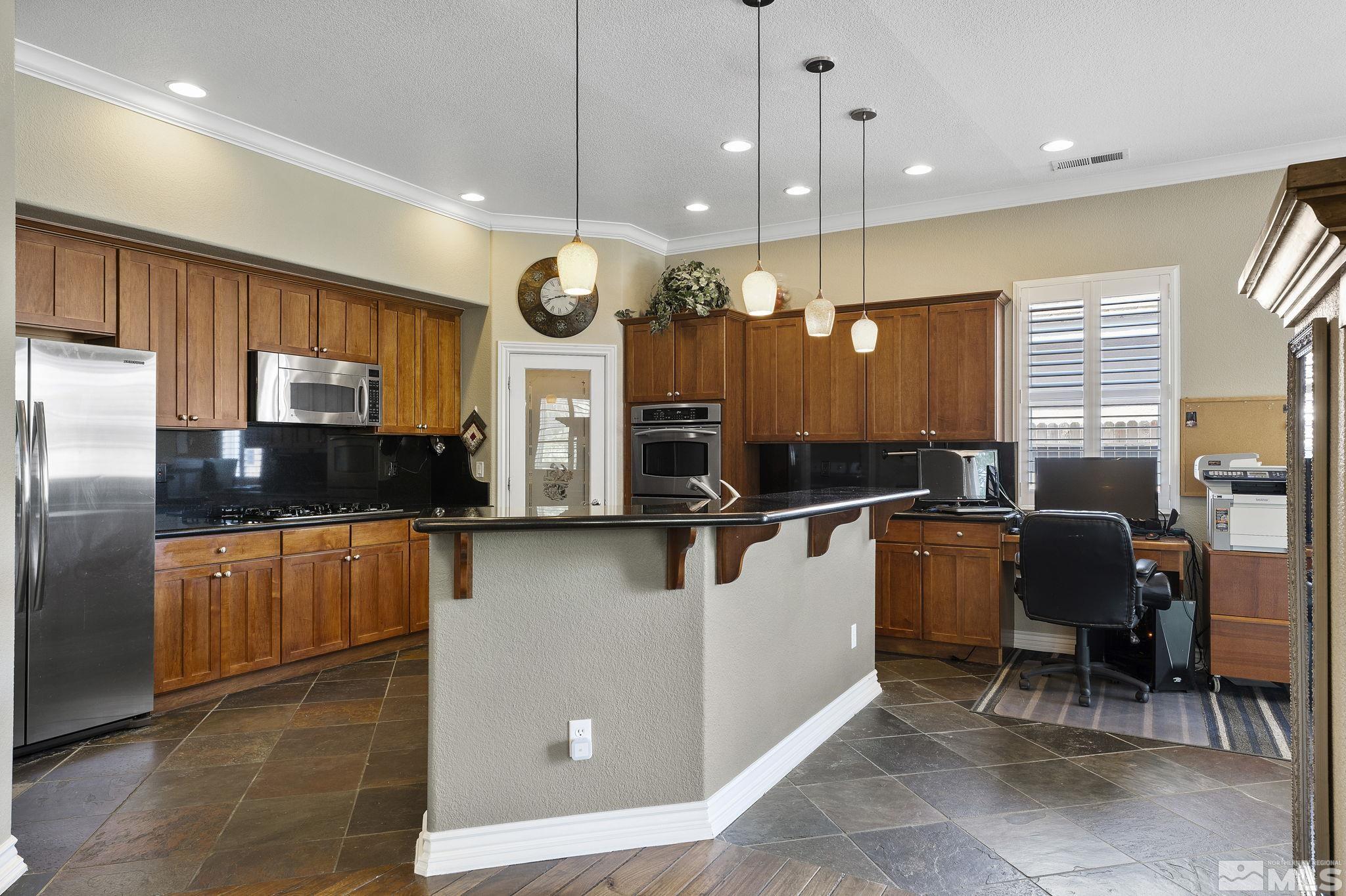10080 Goler Wash Court Reno, NV 89521 - Photo 10 of 40 a kitchen with stainless steel appliances kitchen island granite countertop a stove a sink a dining table and chairs with wooden floor