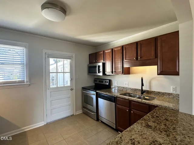 a kitchen with granite countertop a sink stainless steel appliances and cabinets