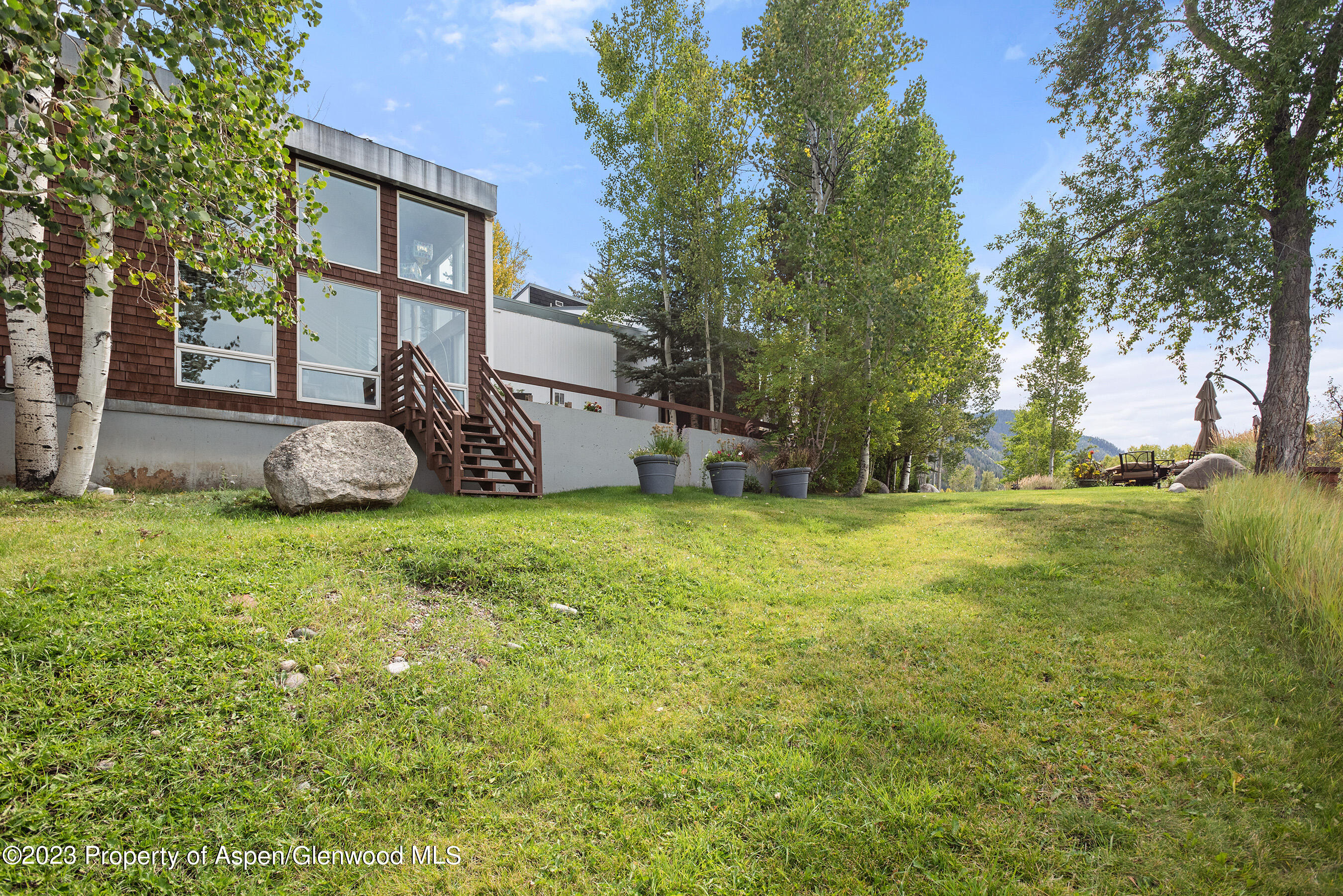 81 Meadows Trustee Road Aspen, CO 81611 - Photo 15 of 26 a view of a backyard with table and chairs and a large tree
