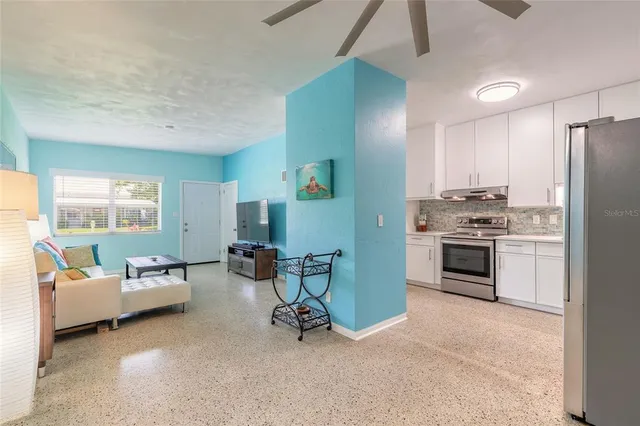 a living room with furniture white walls and kitchen view
