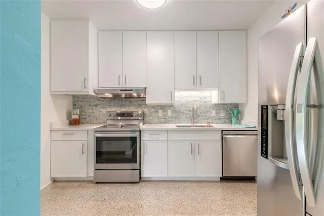 a kitchen with stainless steel appliances granite countertop a stove a refrigerator and a white cabinets