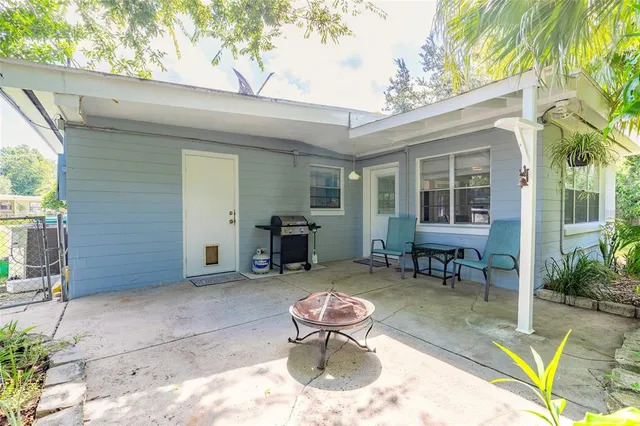 a view of a patio with table and chairs potted plants and a large tree