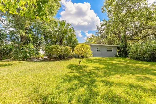 a white house with a big yard and large trees
