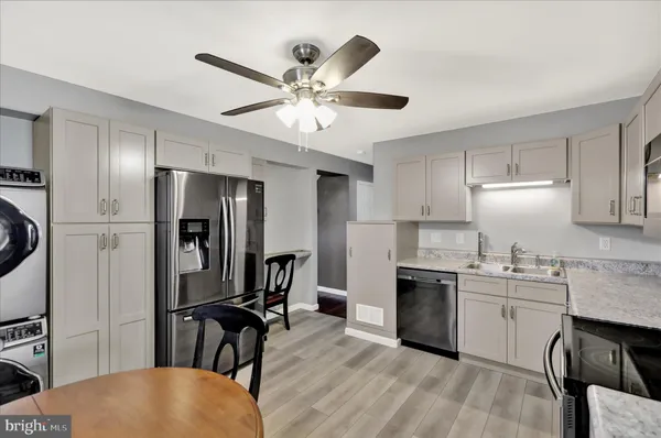 a kitchen with stainless steel appliances granite countertop a refrigerator a sink a stove and white cabinets with wooden floor