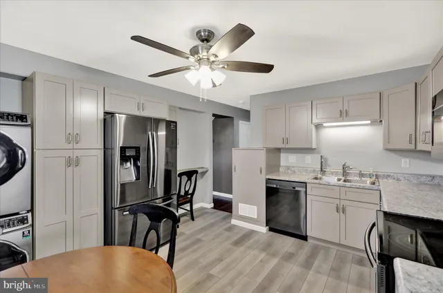 a kitchen with stainless steel appliances granite countertop a refrigerator a sink a stove and white cabinets with wooden floor