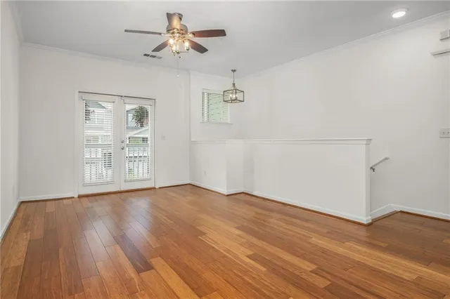 an empty room with wooden floor chandelier fan and windows