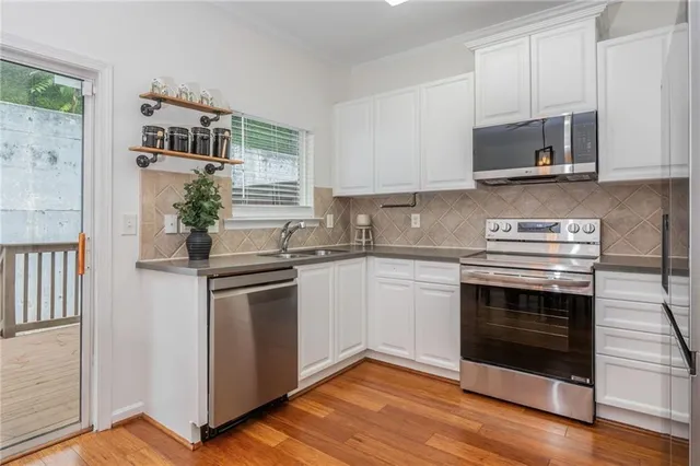a kitchen with granite countertop white cabinets stainless steel appliances and wooden floor