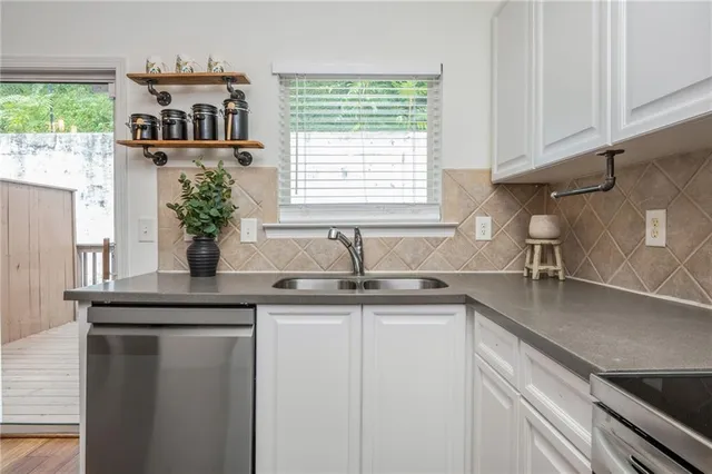 a kitchen with stainless steel appliances granite countertop a sink a window and a counter space