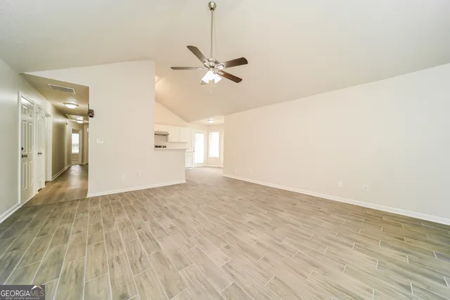 a view of empty room with wooden floor and fan