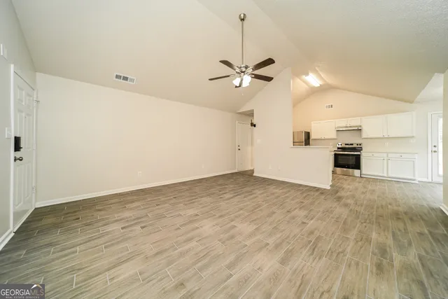 a view of empty room with wooden floor and ceiling fan