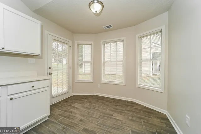 an empty room with wooden floor and windows