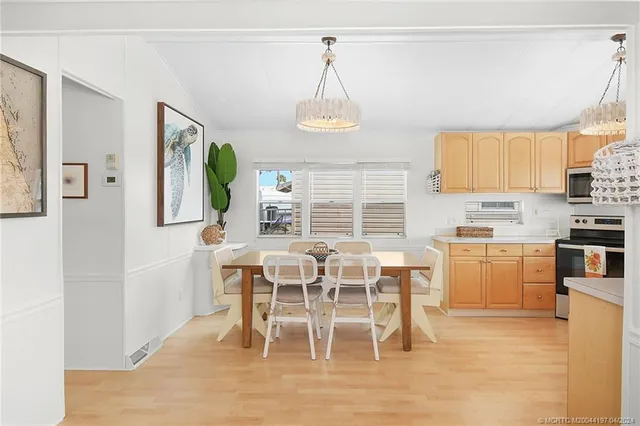 a kitchen with stainless steel appliances kitchen island granite countertop a refrigerator a stove top oven a sink dishwasher a dining table and chairs with wooden floor