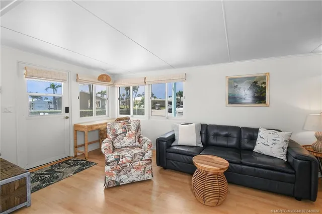 a living room with furniture kitchen view and a large window