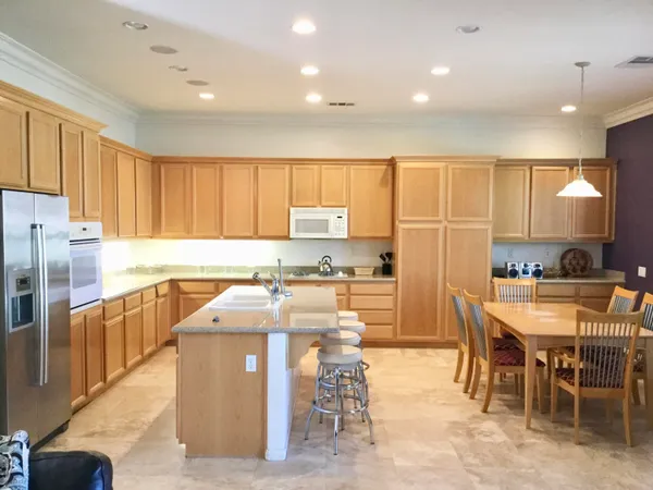 a kitchen with stainless steel appliances granite countertop a table chairs sink and cabinets