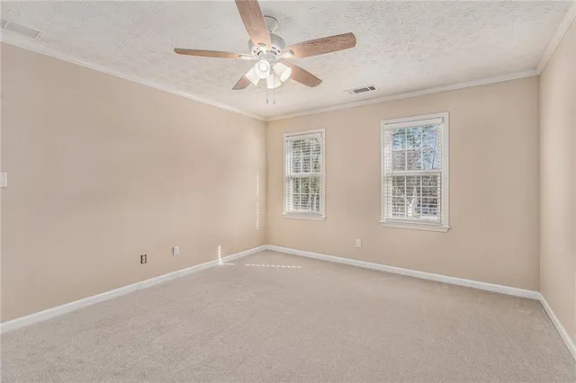 an empty room with chandelier fan and windows