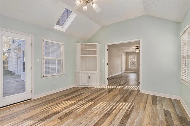 an empty room with wooden floor cabinet and windows