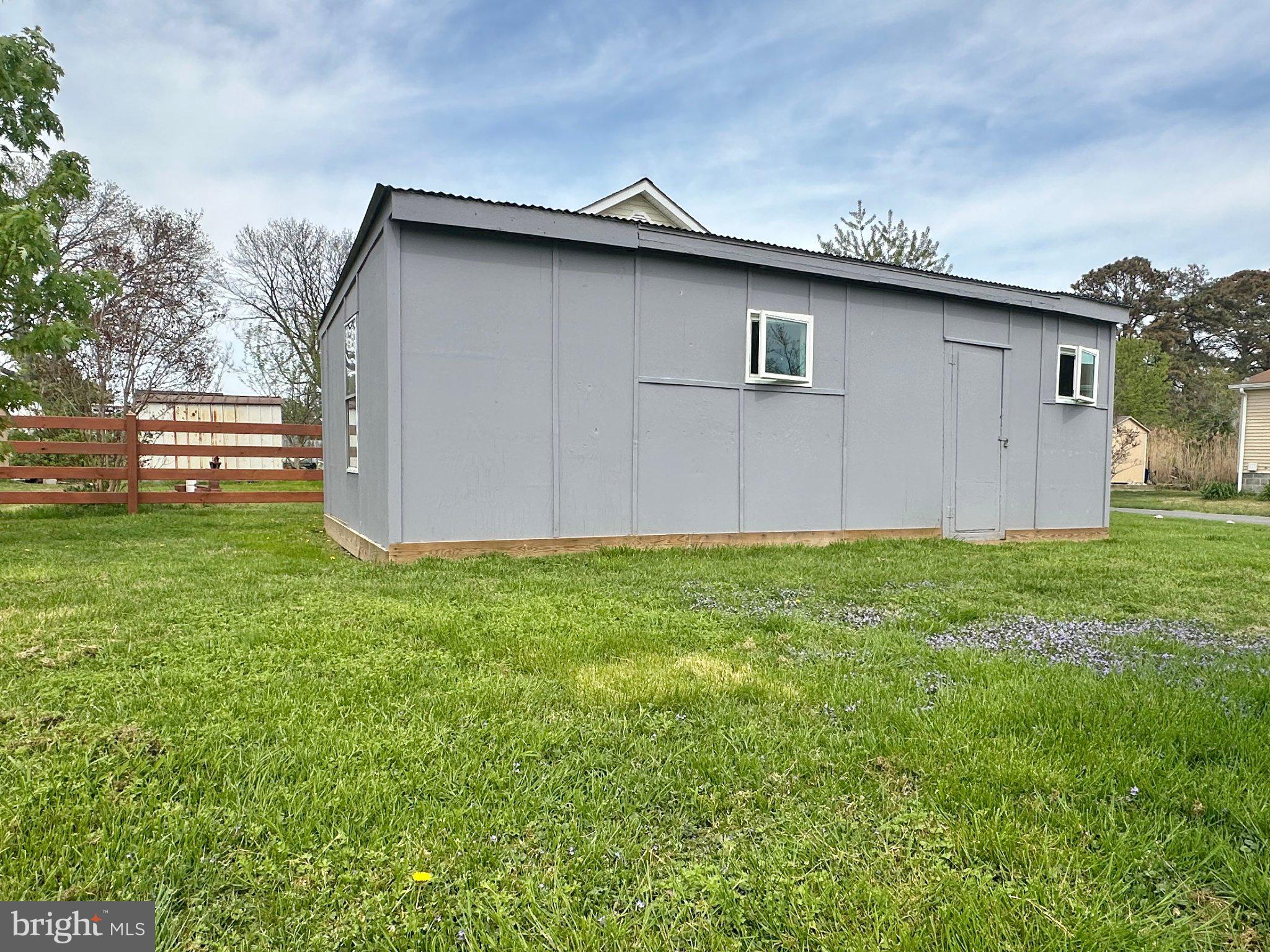 21530 Coopertown Road Tilghman, MD 21671 - Photo 4 of 17 Charming gray shed in a lush yard.