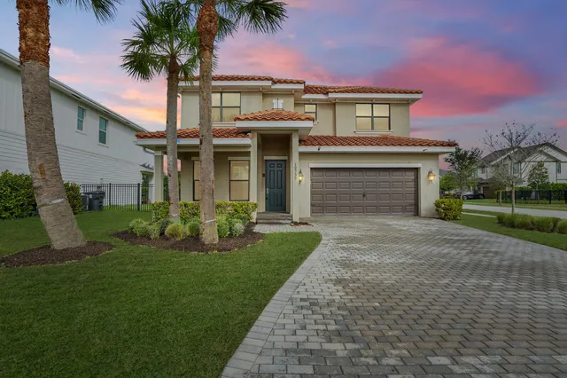 front view of a house with a yard and palm trees