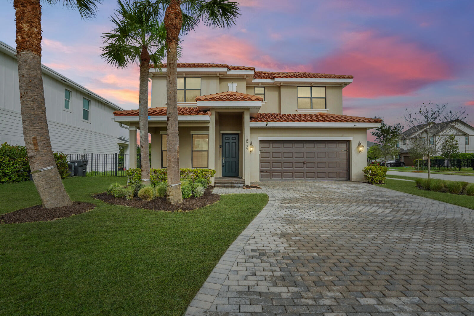 front view of a house with a yard and palm trees