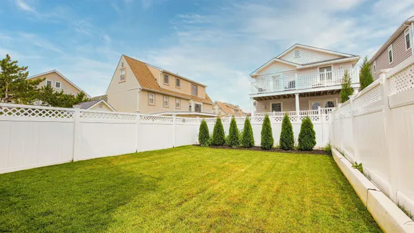 a view of a white house next to a yard with potted plants