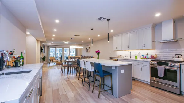 a kitchen with a table chairs wooden floors and stainless steel appliances