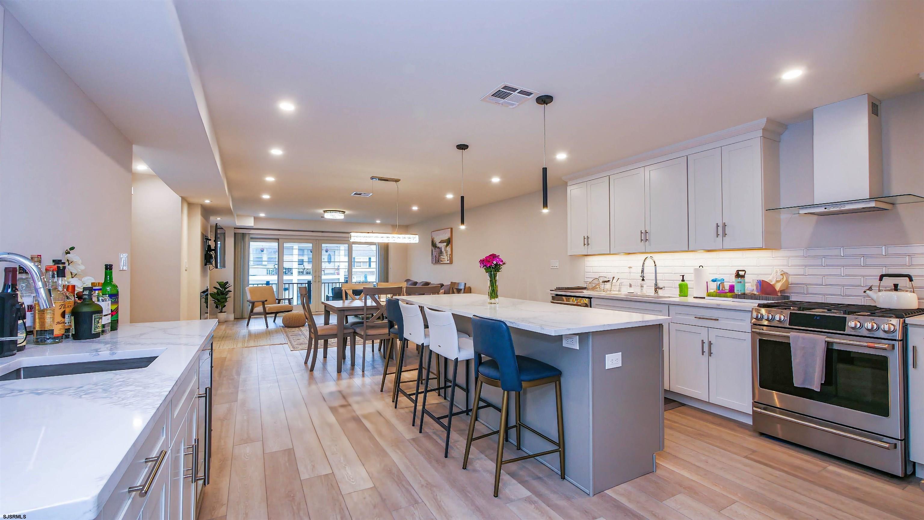 15 North Jefferson Avenue, Unit B Margate City, NJ 08402 - Photo 4 of 13 a kitchen with a table chairs wooden floors and stainless steel appliances