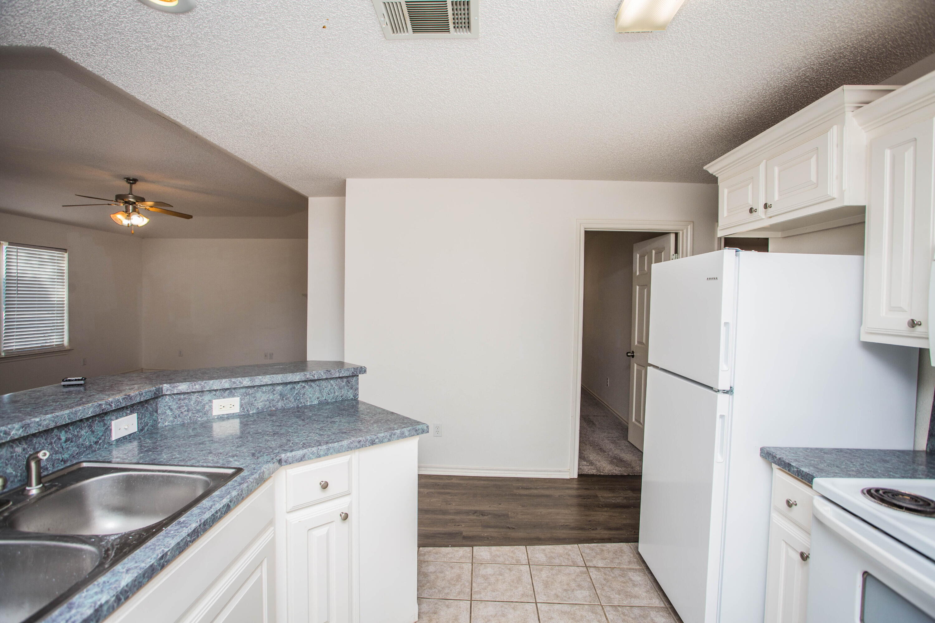 3114 111th Street Lubbock, TX 79423 - Photo 12 of 26 a kitchen with a sink a refrigerator and cabinets