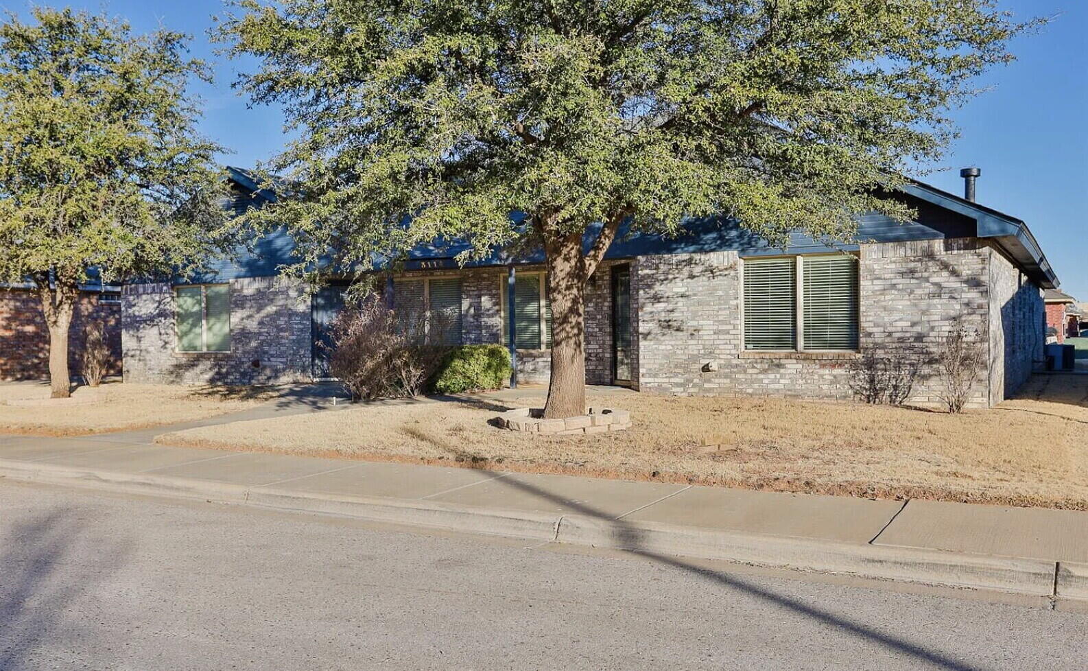 3114 111th Street Lubbock, TX 79423 - Photo 2 of 26 a backyard of a house with large trees and plants