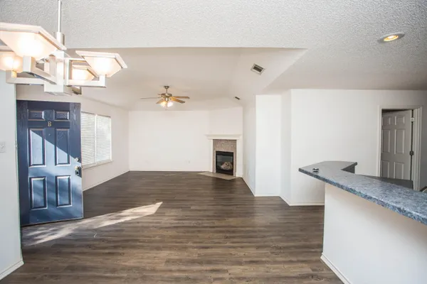 an empty room with wooden floor fireplace and windows
