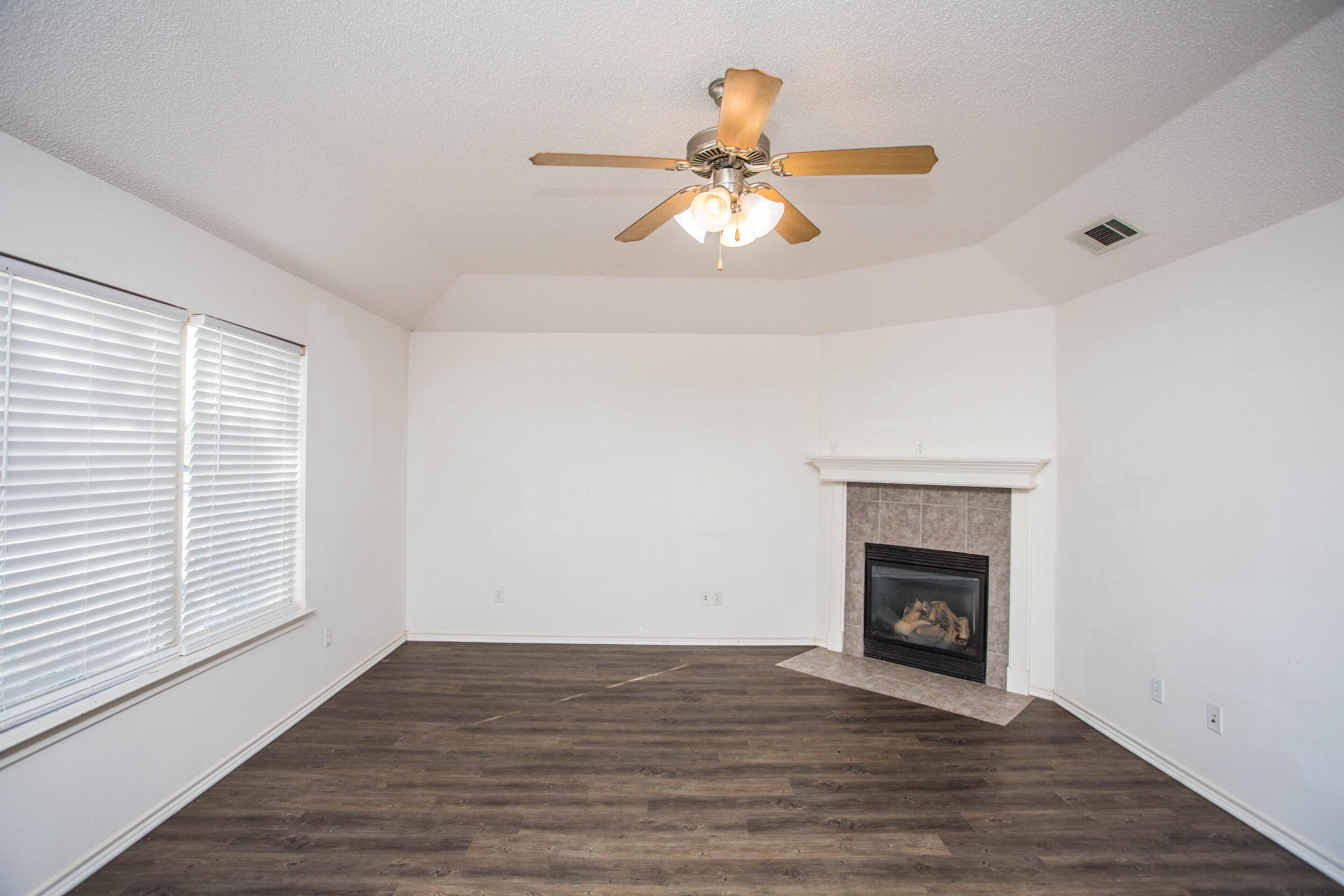 3114 111th Street Lubbock, TX 79423 - Photo 4 of 26 an empty room with wooden floor fireplace and windows