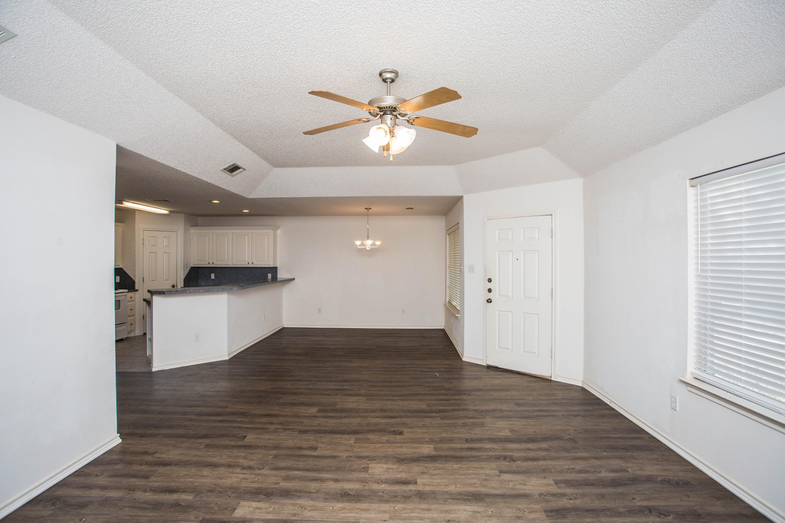 3114 111th Street Lubbock, TX 79423 - Photo 6 of 26 a view of an empty room and kitchen view with wooden floor