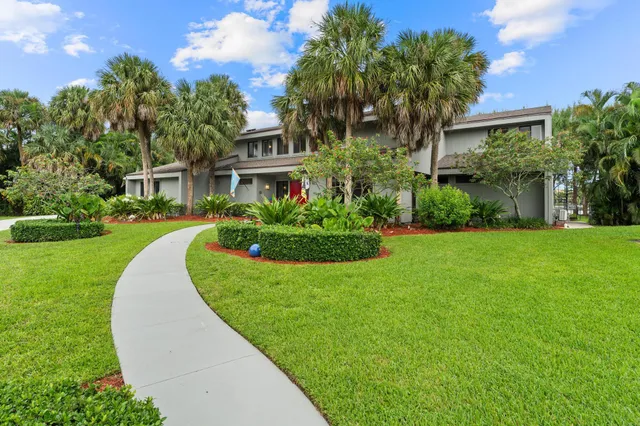 a front view of a house with a yard and potted plants