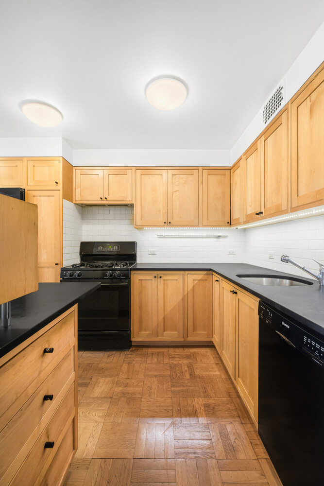 207 East 74th Street, Unit 5JH Manhattan, NY 10021 - Photo 4 of 21 a kitchen with granite countertop a stove a sink and a refrigerator