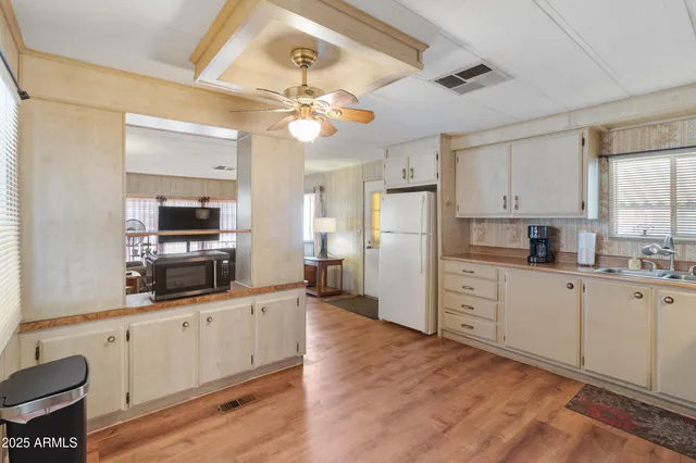 a kitchen with granite countertop a refrigerator a sink and white cabinets