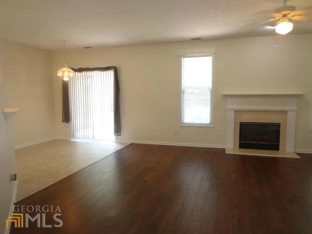 an empty room with wooden floor fireplace and windows
