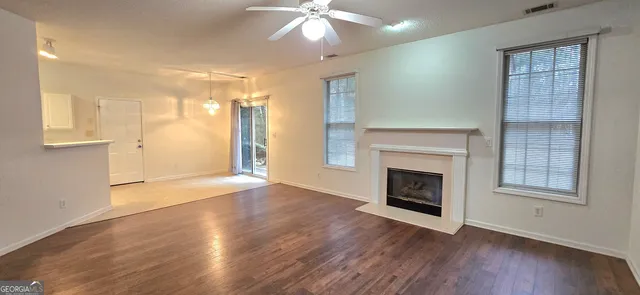 an empty room with wooden floor cabinet and windows