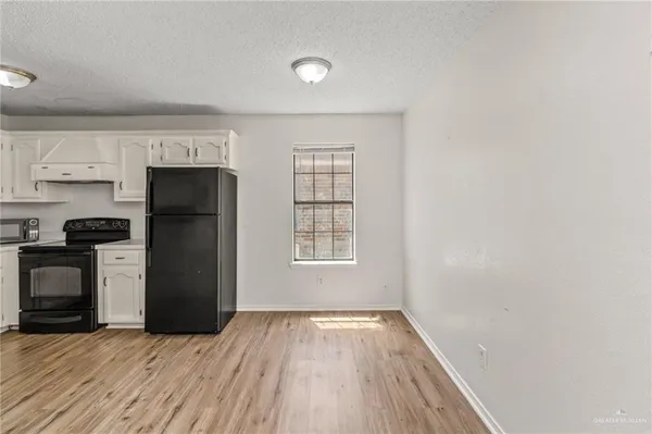 a view of a kitchen with a refrigerator a stove top oven and cabinets