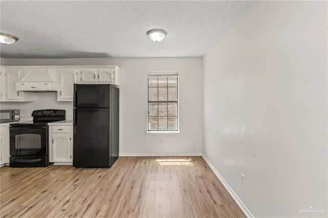 a view of a kitchen with a refrigerator a stove top oven and cabinets