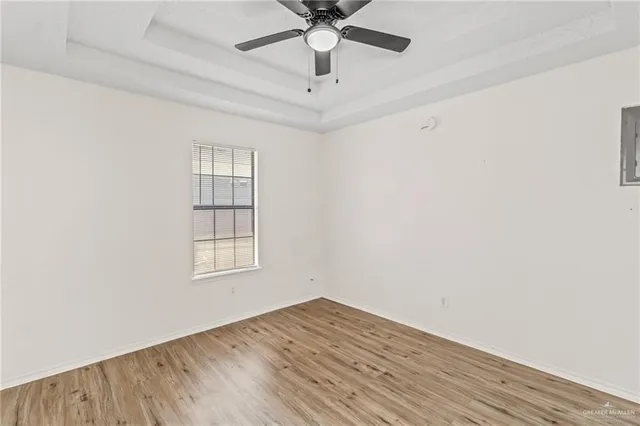 an empty room with wooden floor chandelier fan and windows