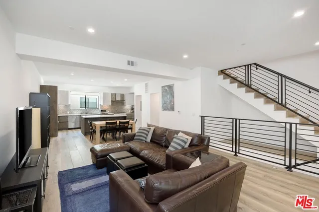 a living room with furniture kitchen view and a flat screen tv