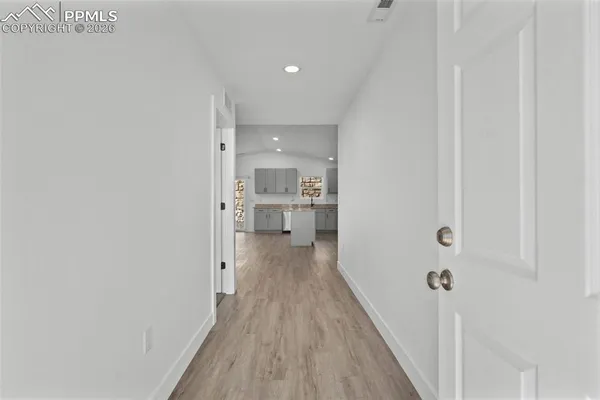a view of a hallway with wooden floor and a bathroom