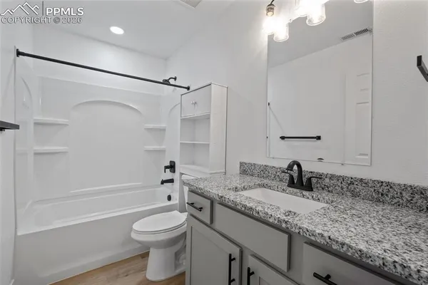 a bathroom with a granite countertop sink toilet and shower
