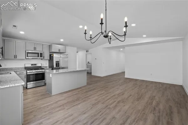 a kitchen with stainless steel appliances a refrigerator a stove a sink and white cabinets with wooden floor