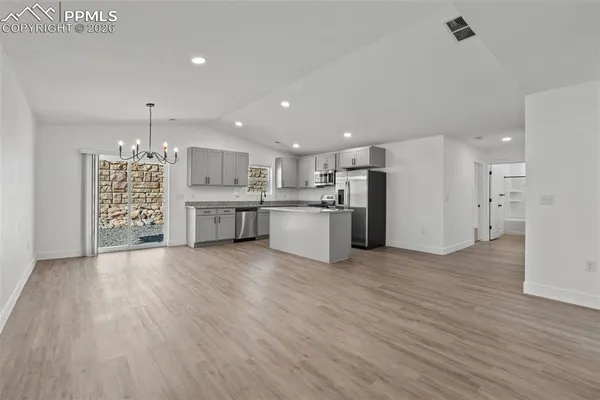 a view of a kitchen with a refrigerator wooden floor and a window