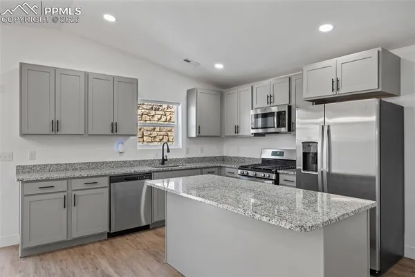 a kitchen with stainless steel appliances granite countertop a sink stove microwave and refrigerator