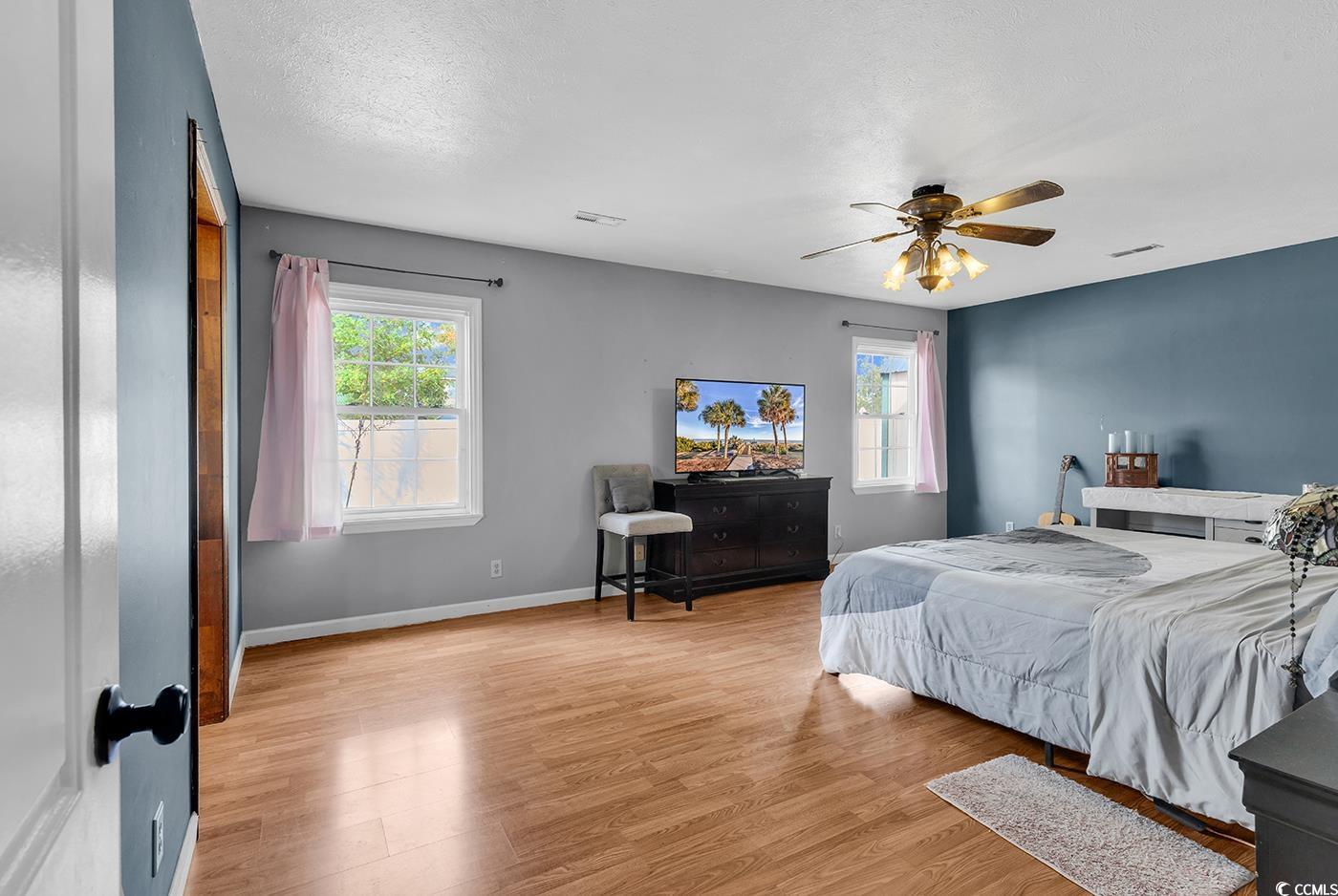 4 Plantation Road Myrtle Beach, SC 29588 - Photo 14 of 40 Bedroom featuring multiple windows, light wood-style flooring, ceiling fan, and a textured ceiling