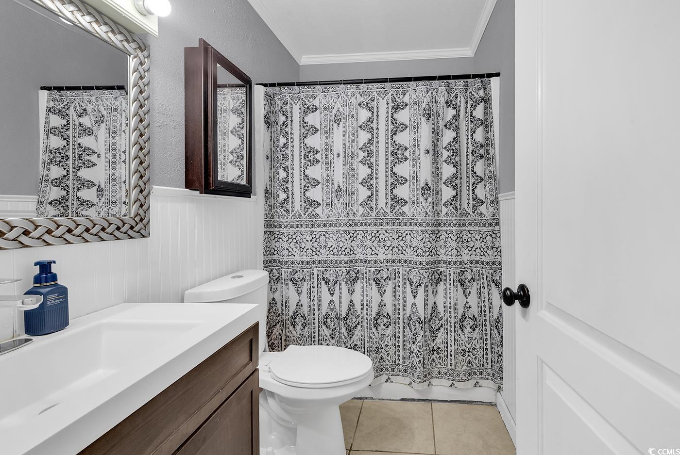 4 Plantation Road Myrtle Beach, SC 29588 - Photo 25 of 40 Full bathroom featuring vanity, crown molding, light tile patterned floors, curtained shower, and a wainscoted wall